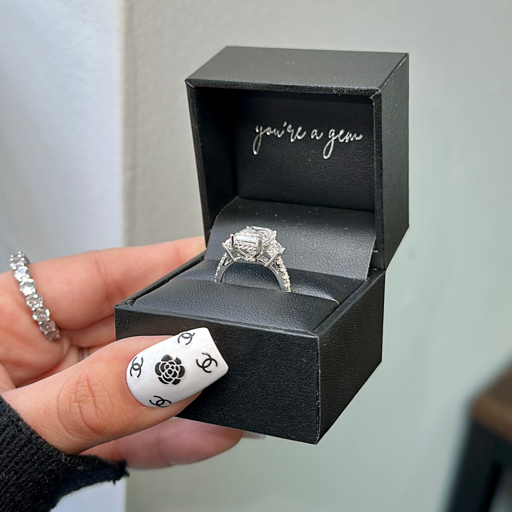 Close-up of Fiona 2.5ct emerald cut moissanite engagement ring on solid gold band”- elizabeth + Bern