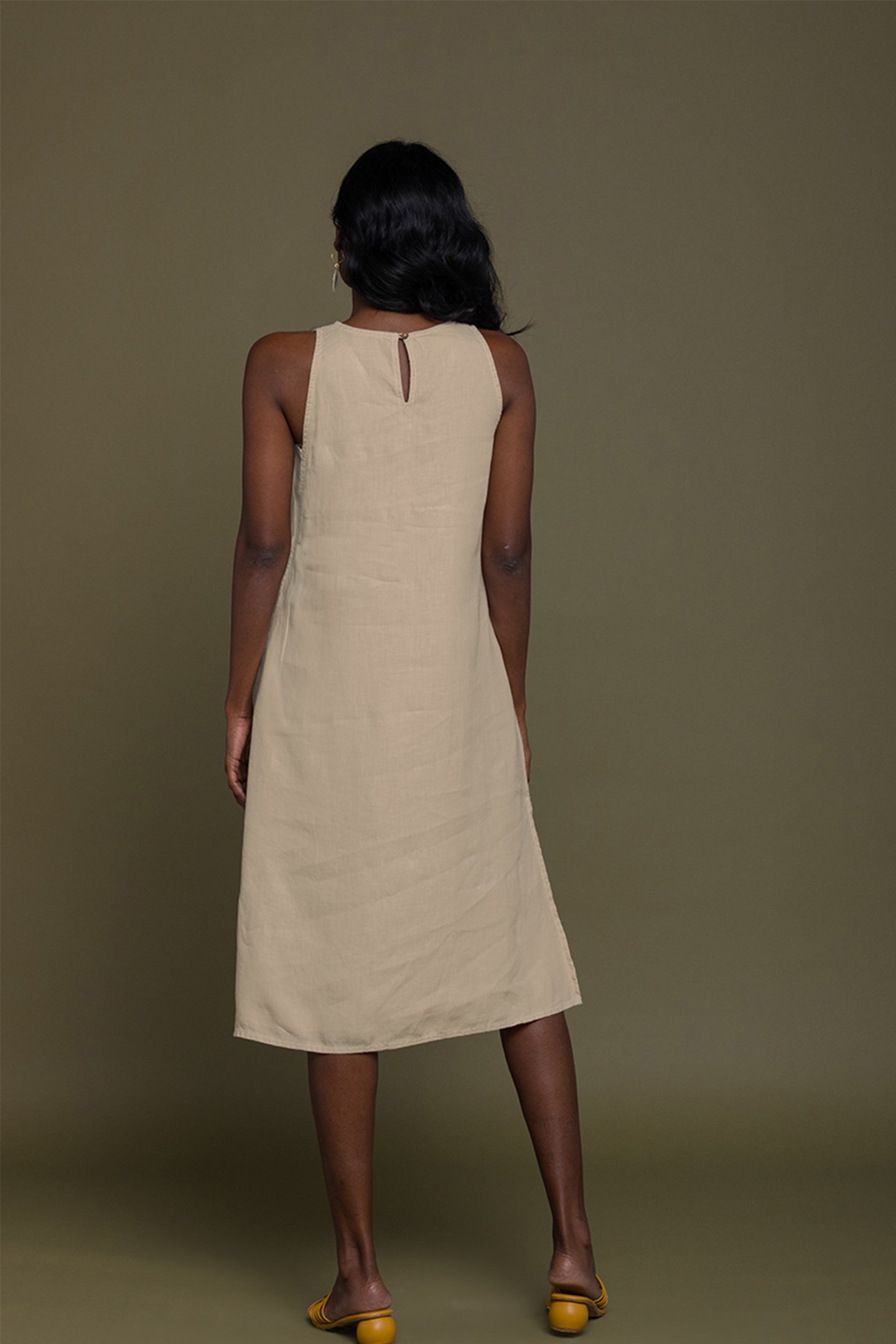 Woman wearing a beige dress against a brown background