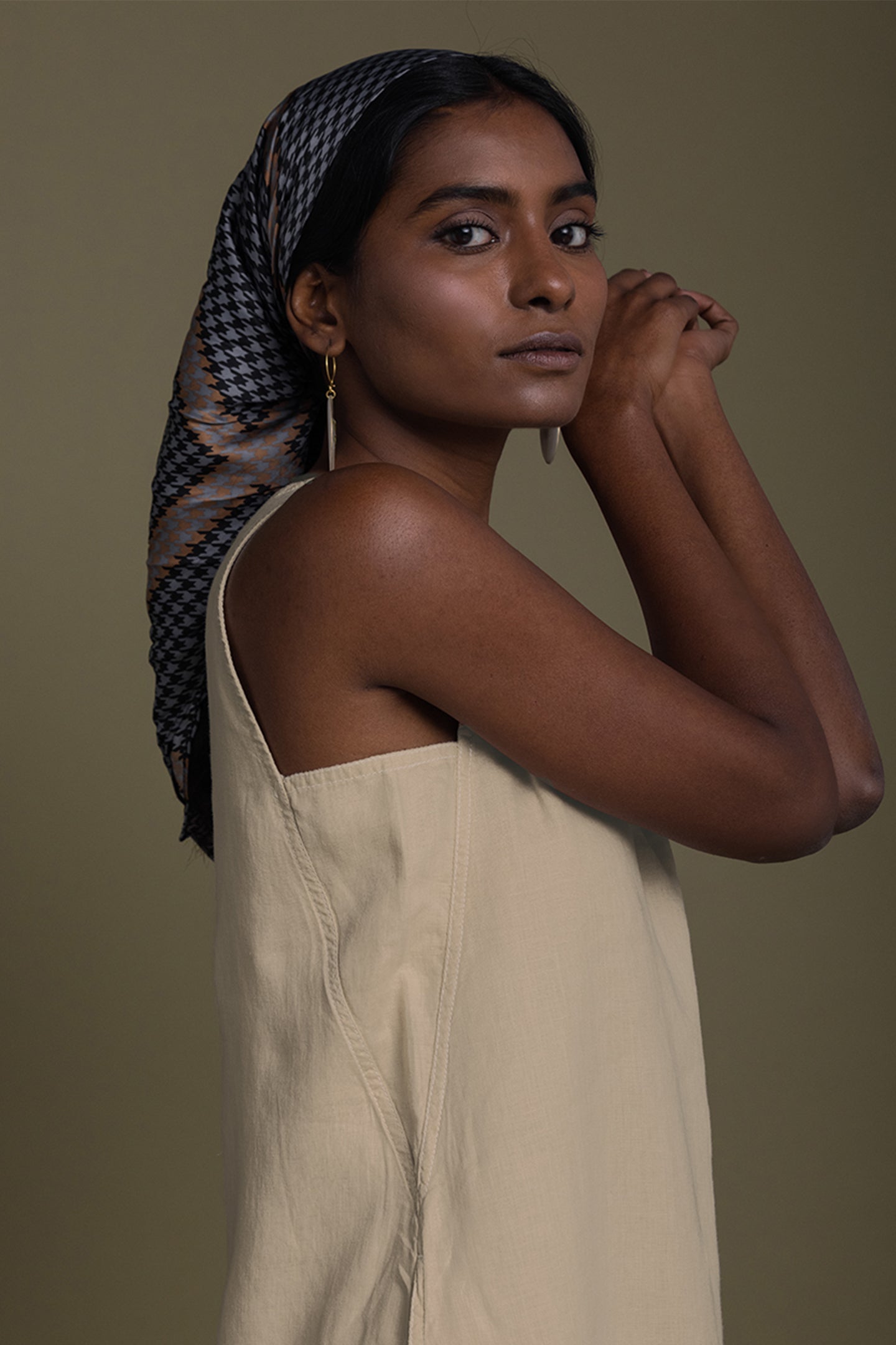 Woman wearing a beige dress and patterned headscarf against a brown background Reading Tea Leaves midi dress in neutral beige sustainable hemp with A-line fit, side slits and practical pockets