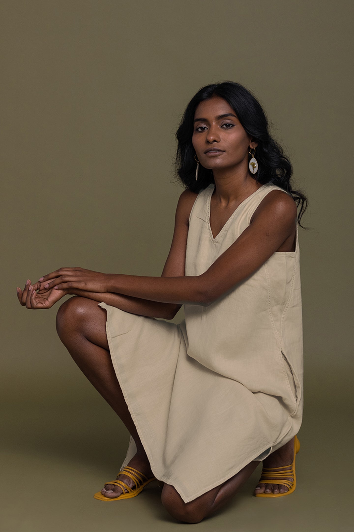 Woman wearing a beige dress sitting on a brown background Reading Tea Leaves midi dress in neutral beige sustainable hemp with A-line fit, side slits and practical pockets
