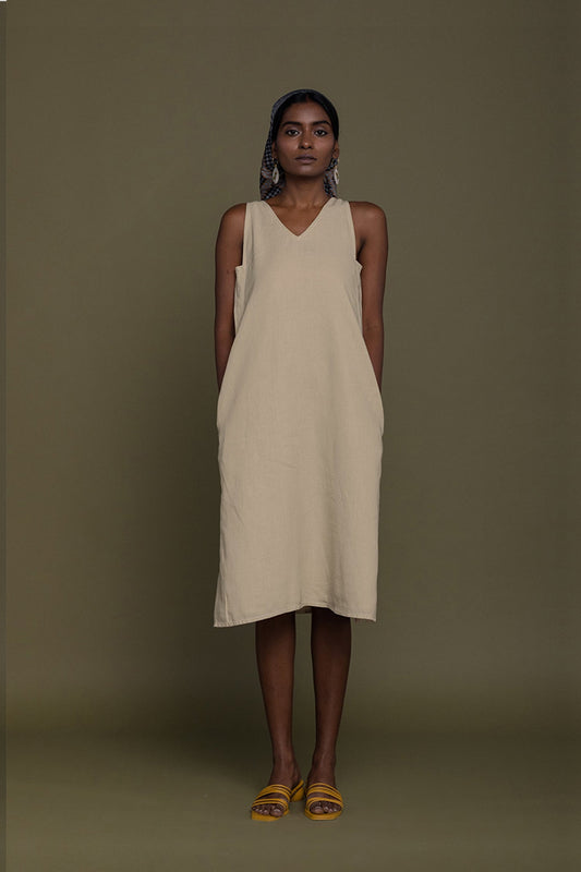 Woman wearing a beige sleeveless dress against a plain background Reading Tea Leaves midi dress in neutral beige sustainable hemp with A-line fit, side slits and practical pockets