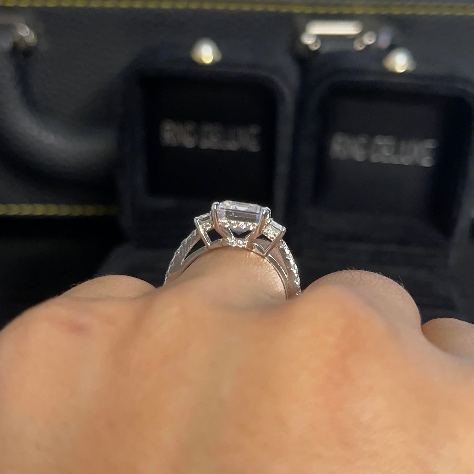 Three-stone emerald cut moissanite ring with side stones in luxury ring box- elizabeth + Bern
