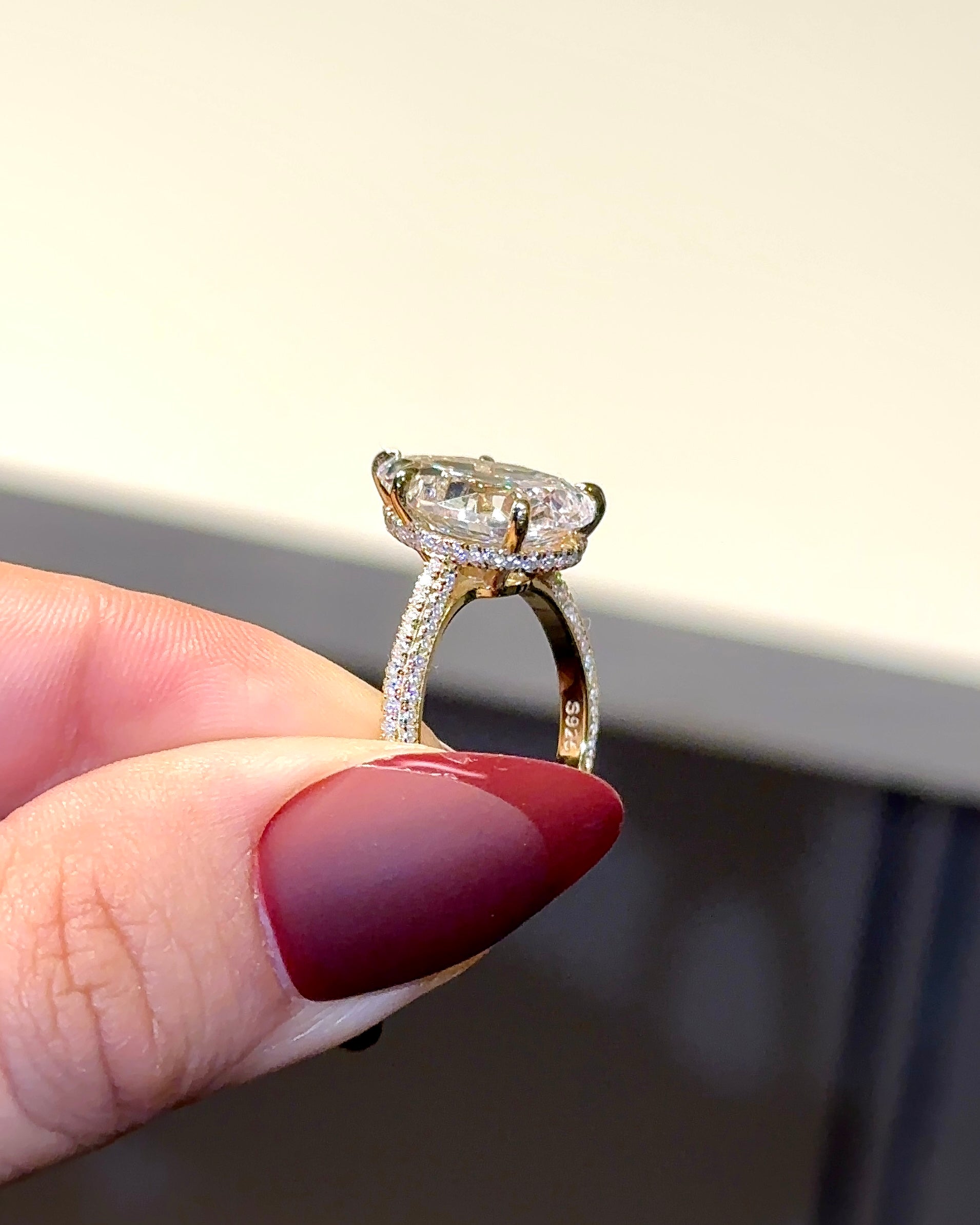 Diamond ring held between fingers with a blurred background