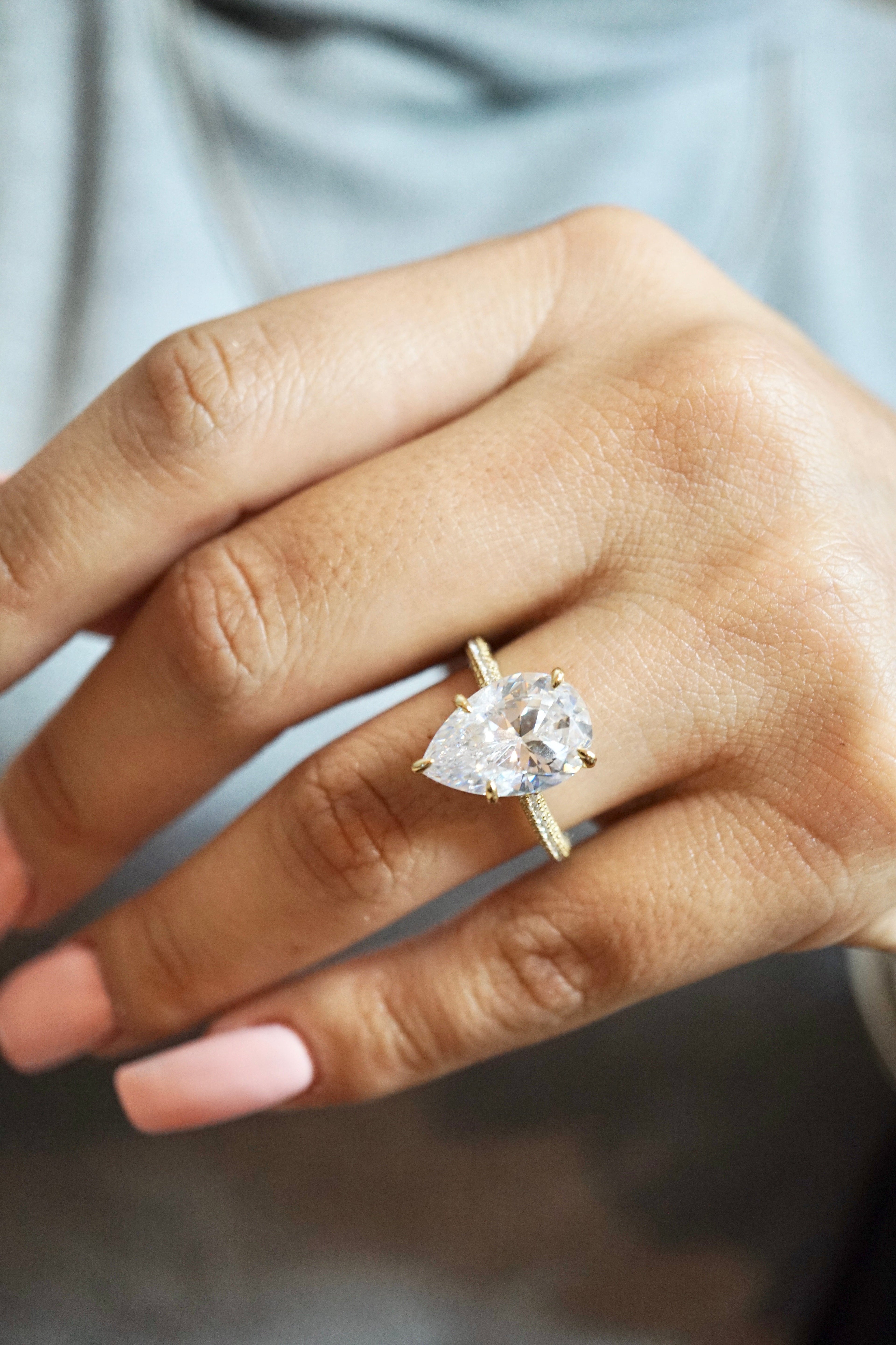 Close-up of a hand wearing a diamond ring with a blurred background