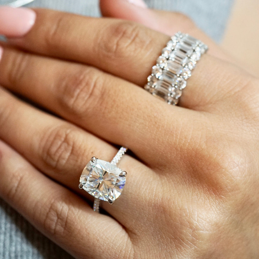 Close-up of a hand wearing two diamond rings on a gray background