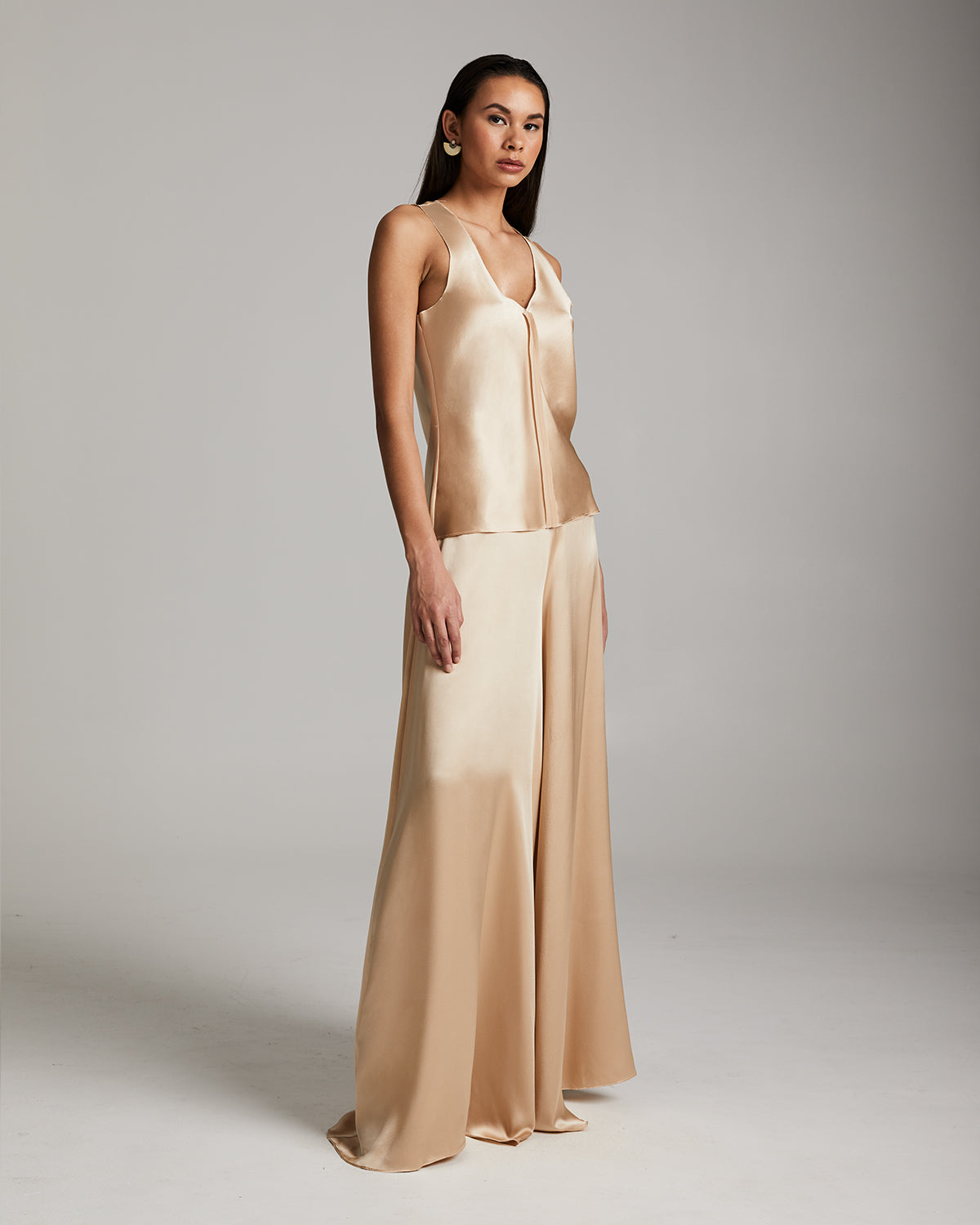 Woman wearing a beige evening gown against a plain background Silk palazzo pants in flowing charmeuse with dramatic wide leg silhouette, ethically made in NYC by VOZ