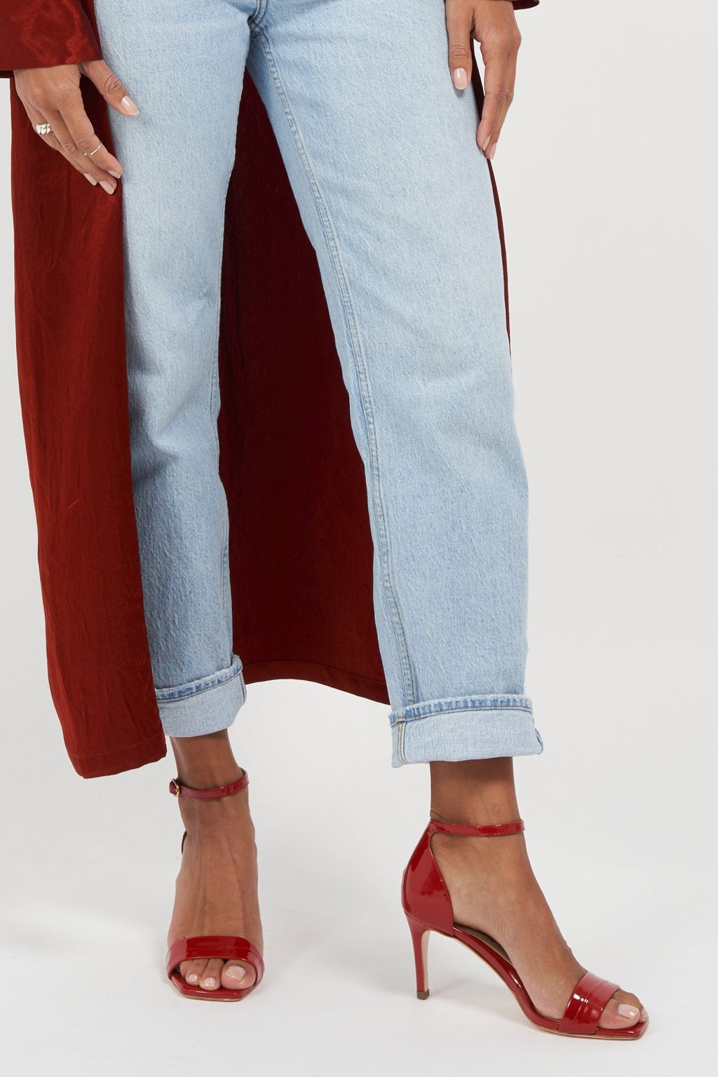 Person wearing light blue jeans and red shoes on a white background
