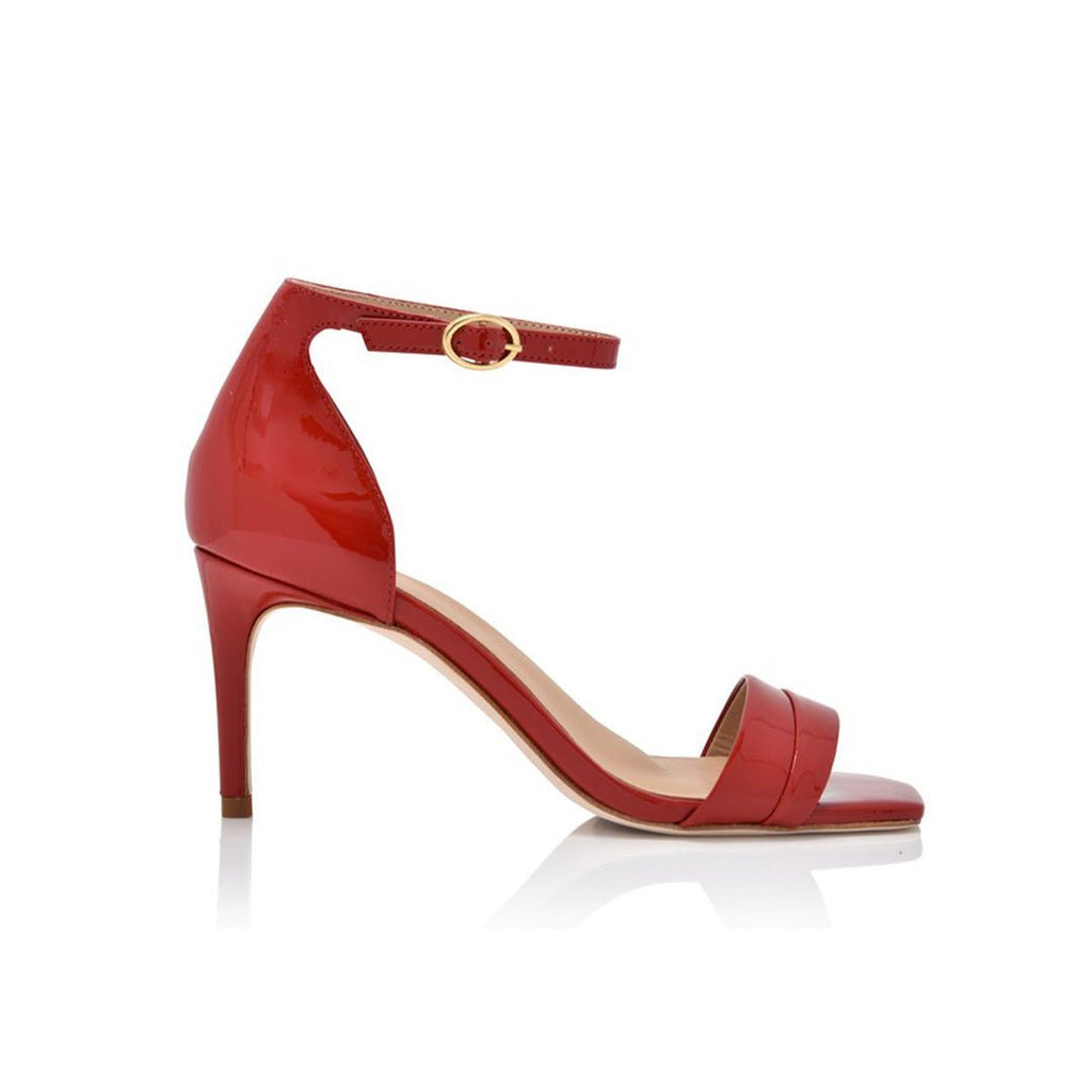 Red high-heeled sandal with a gold buckle on a white background